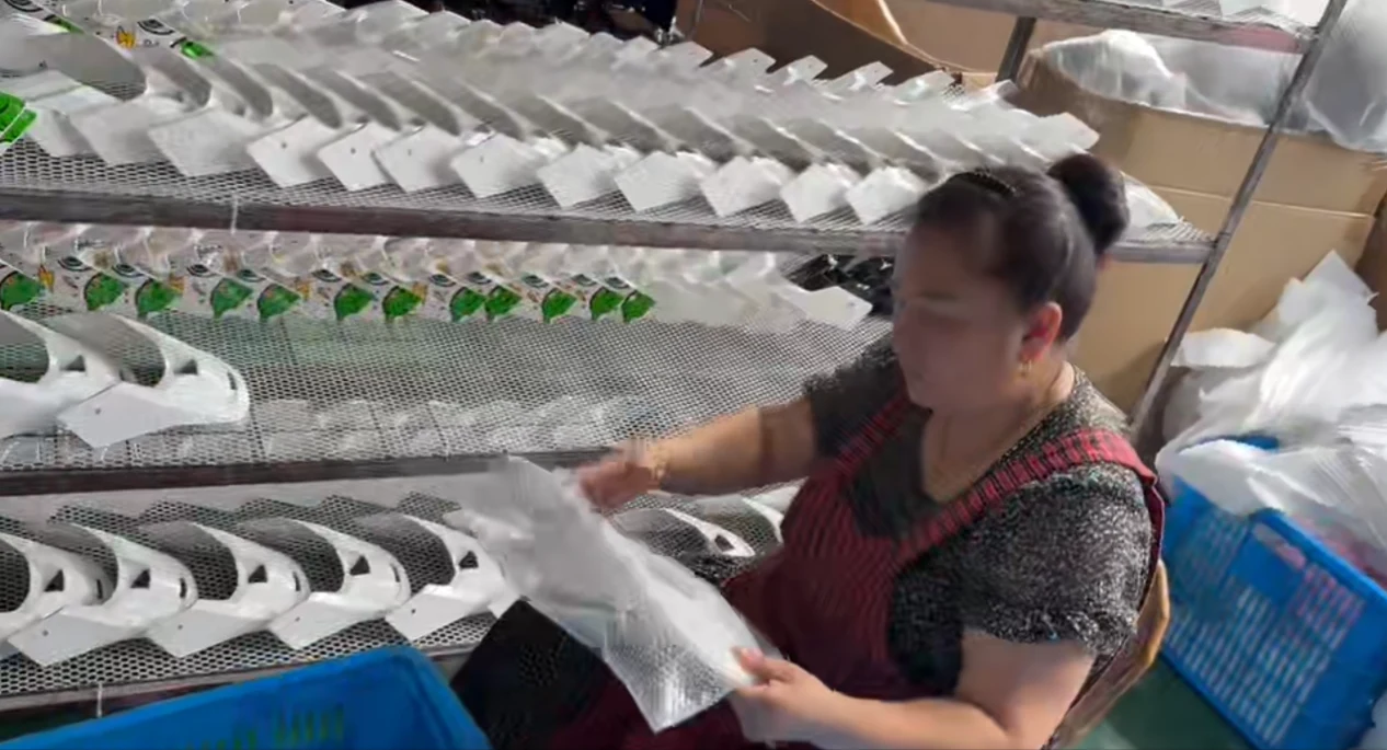 Worker in a red apron inspecting the clear coat finish on helmet parts