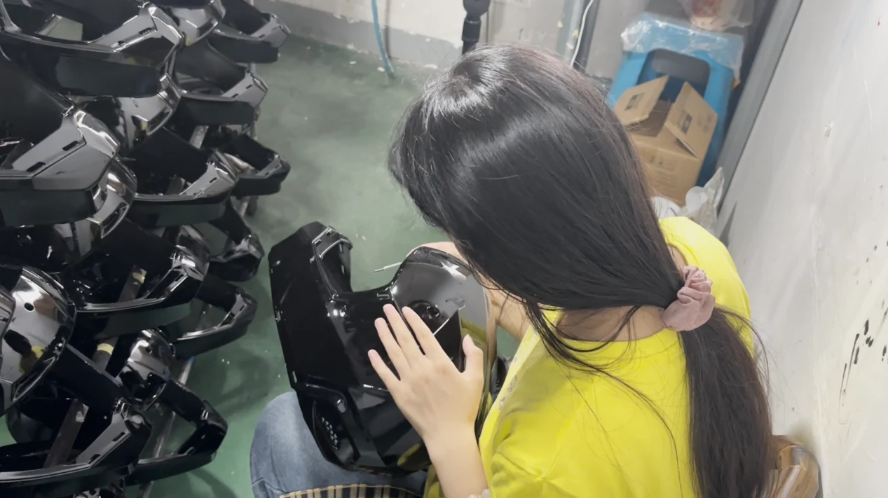 Worker in yellow checking the color paint on helmet shells for runs, thin spots and dirt