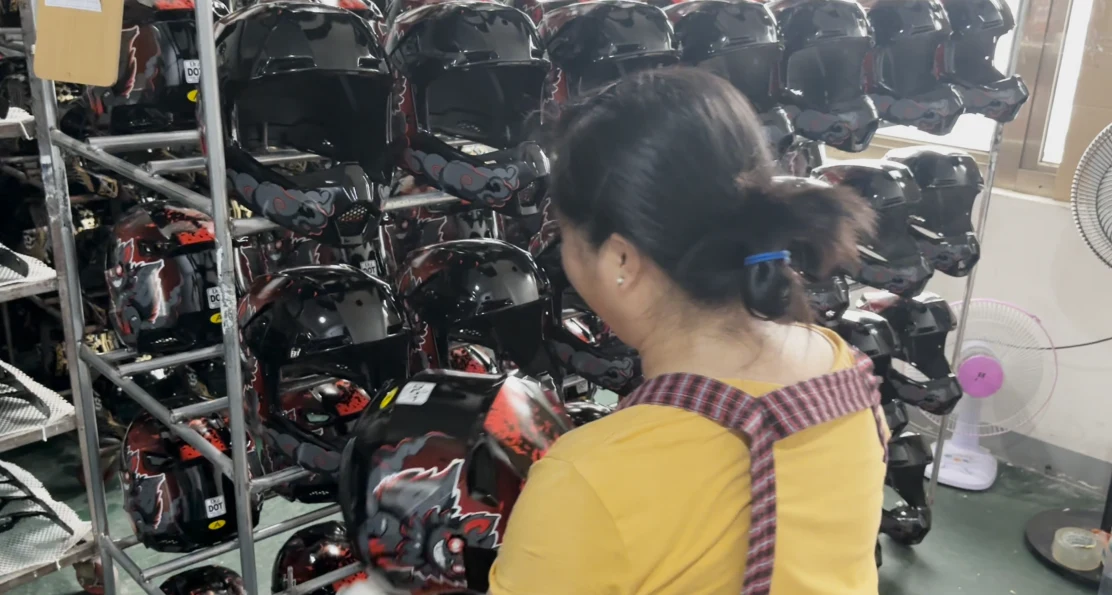 Worker checking decals on helmets for bubbles, tears and position